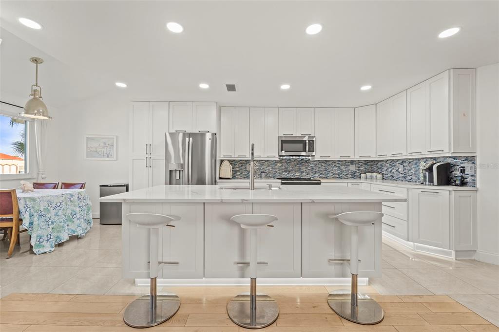 2385 Hanover Drive Dunedin, FL 34698 - Photo 4 of 87 a kitchen with stainless steel appliances granite countertop a stove a sink a refrigerator and white cabinets with wooden floor