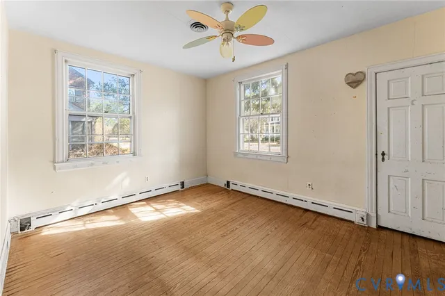 a view of an empty room with a window and wooden floor