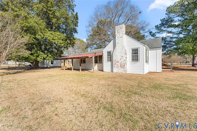 a view of house with yard and trees in the background