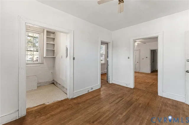 an empty room with wooden floor and windows