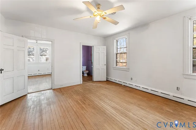 an empty room with windows and ceiling fan