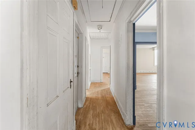 a view of a hallway with wooden floor and a bathroom