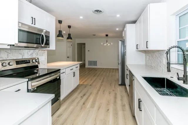 a kitchen with stainless steel appliances a stove sink microwave and cabinets