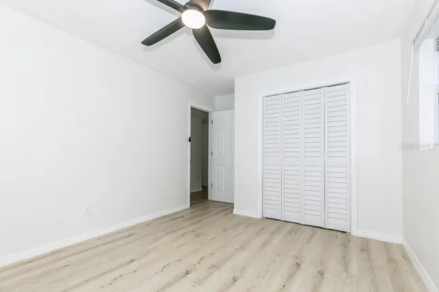 an empty room with closet and a ceiling fan