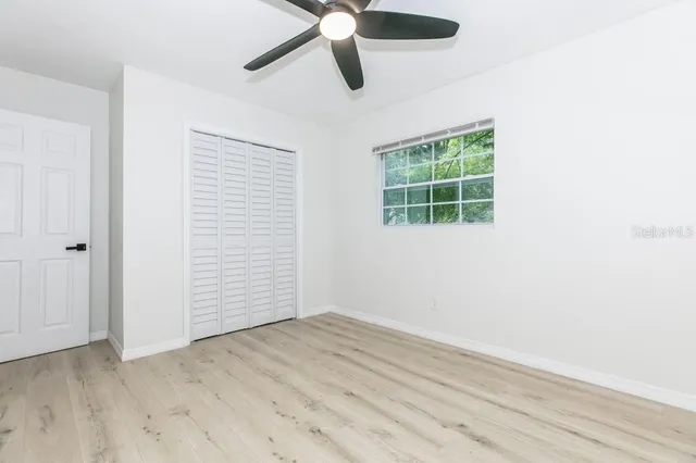 an empty room with wooden floor cabinet and windows