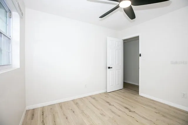 an empty room with a window and a ceiling fan