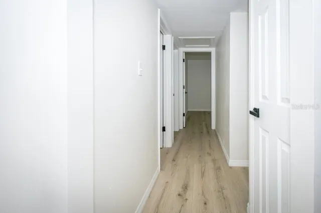 an empty room with wooden floor ceiling fan and windows
