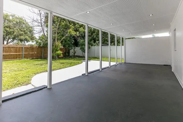 a view of an empty room with floor to ceiling windows and garden