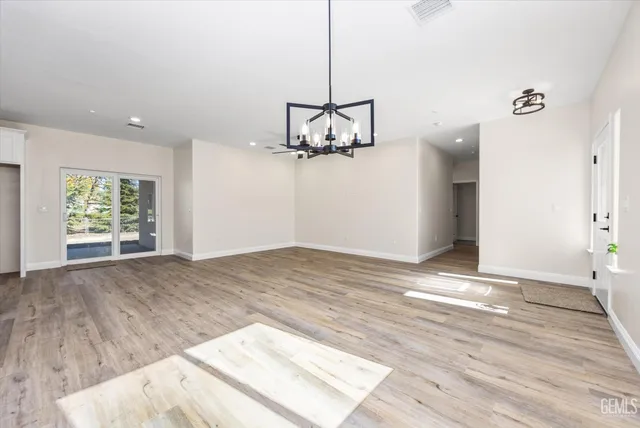 an empty room with wooden floor a ceiling fan and windows