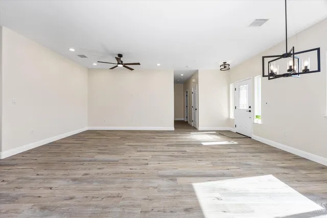 a kitchen with stainless steel appliances kitchen island granite countertop a refrigerator a stove top oven a sink dishwasher and white cabinets with wooden floor