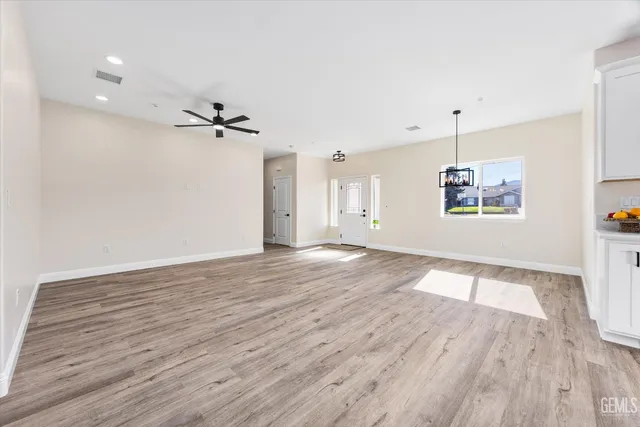 a kitchen with stainless steel appliances kitchen island granite countertop a stove a sink a refrigerator and white cabinets with wooden floor