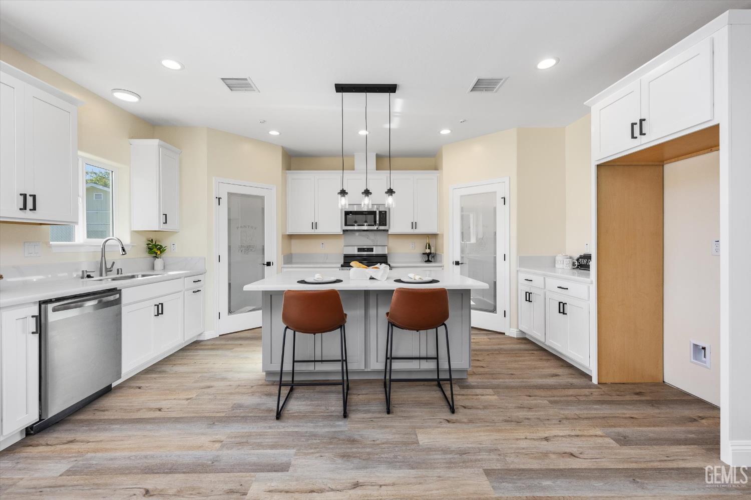 Undisclosed Address Tehachapi, CA 93561 - Photo 23 of 50 a kitchen with stainless steel appliances kitchen island granite countertop a stove a sink a refrigerator and white cabinets with wooden floor