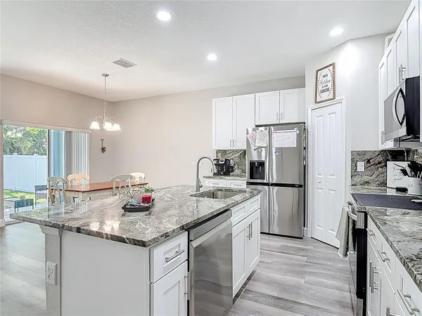 a kitchen with kitchen island granite countertop white cabinets and stainless steel appliances