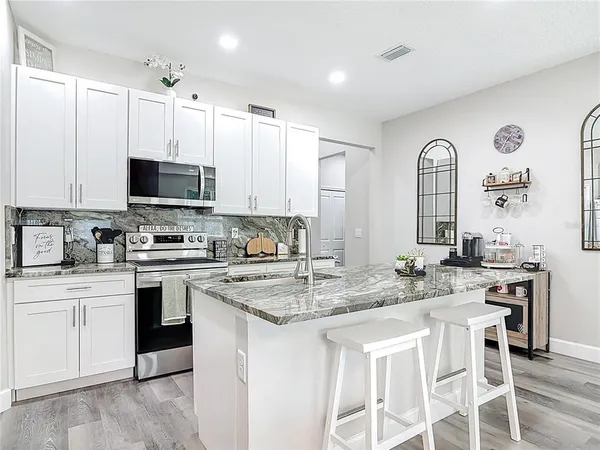 a kitchen with stainless steel appliances granite countertop a sink stove and cabinets