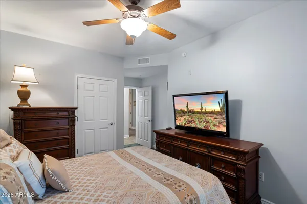 a bedroom with a bed and a flat tv screen on dresser