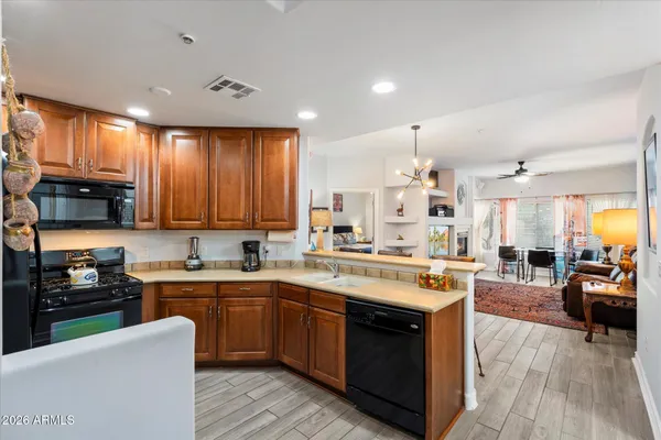 a kitchen with a stove top oven a sink dishwasher a dining table and chairs with wooden floor