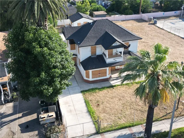 an aerial view of a house with swimming pool and large trees