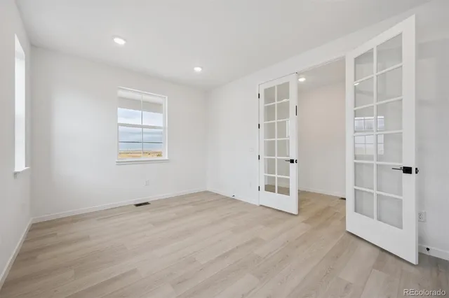 an empty room with wooden floor and windows