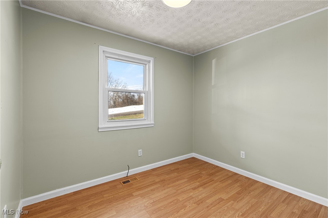 61899 Webb Heights Road Shadyside, OH 43947 - Photo 21 of 39 Empty room with ornamental molding, a textured ceiling, and light wood-type flooring