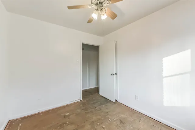 an empty room with a chandelier fan and windows