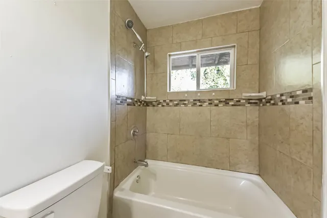 a bathroom with a bathtub a window and a shower