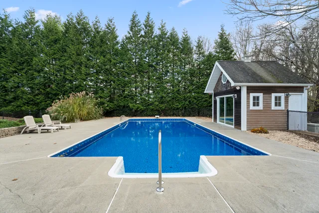 a view of swimming pool with outdoor seating and house in the background