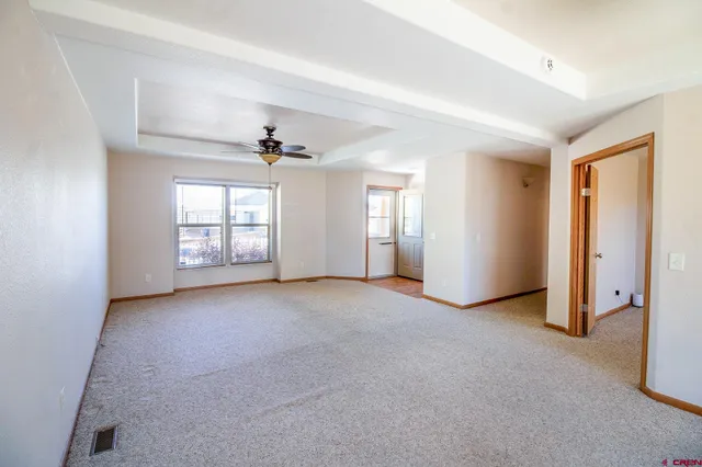 an empty room with windows and ceiling fan