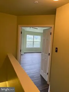 a view of a hallway with wooden floor and a bathroom