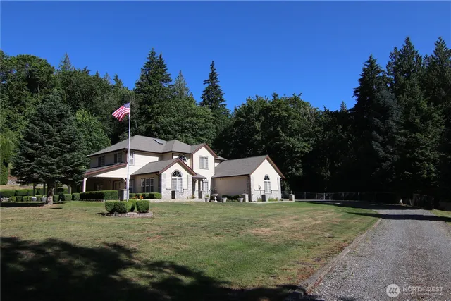 a view of white house with wooden fence and trees around