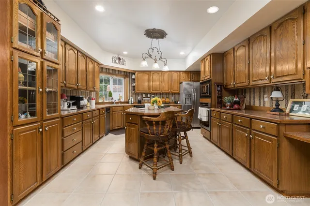a kitchen with stainless steel appliances granite countertop wooden cabinets a table and chairs