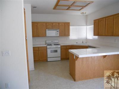 66120 Santa Rosa Road Desert Hot Springs, CA 92240 - Photo 3 of 9 a kitchen that has a sink a stove and a microwave oven in a cabinets