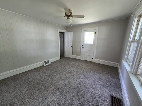 an empty room with windows and fan