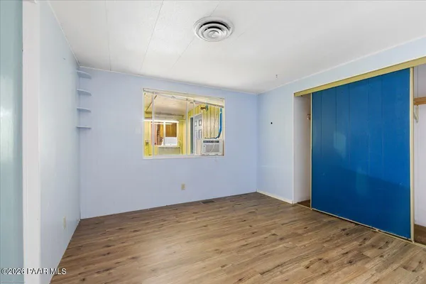 a view of an empty room with wooden floor and a window