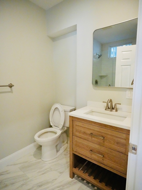 59 7th Street, Unit 1 Cambridge, MA 02141 - Photo 15 of 21 a bathroom with a granite countertop toilet a sink and mirror