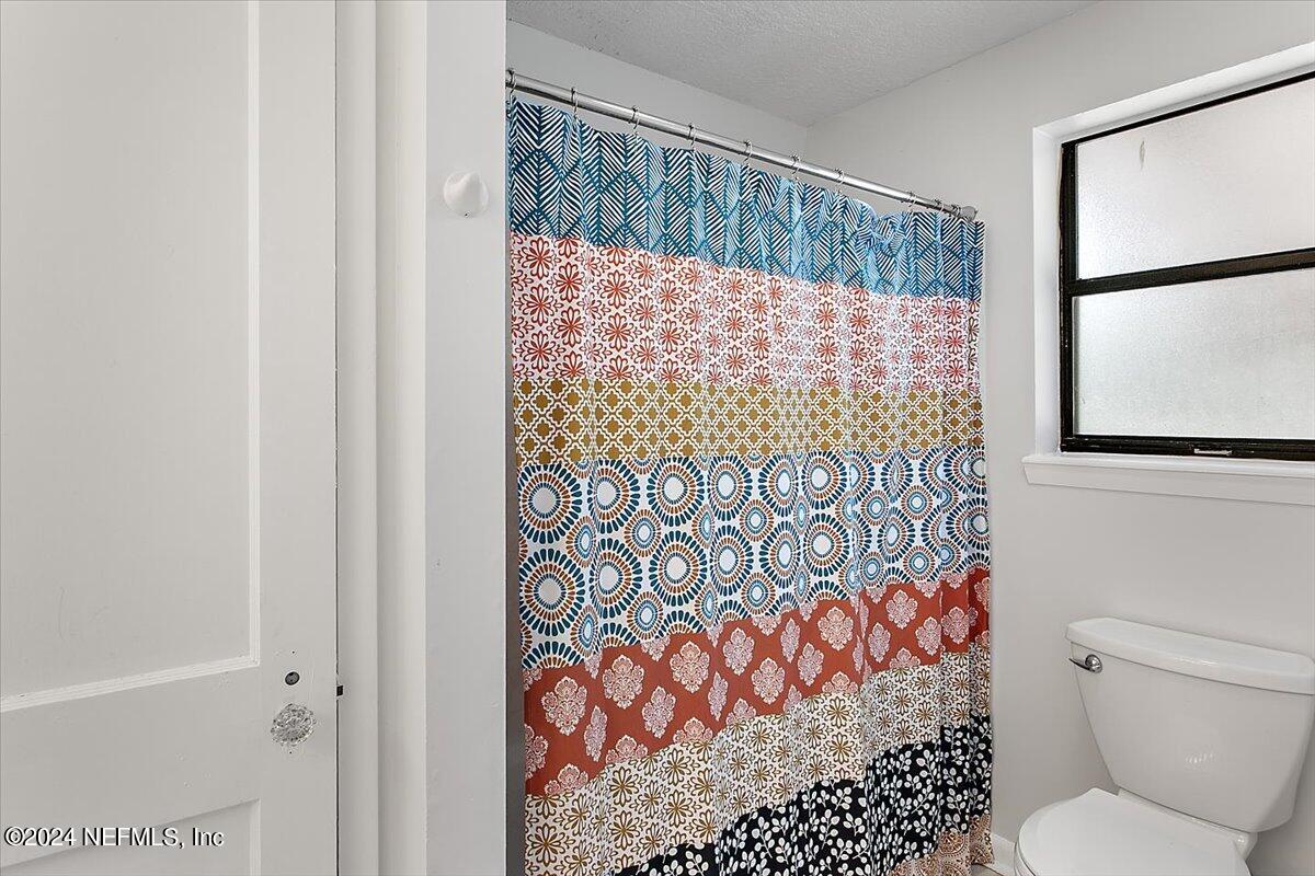 6263 Ricker Road Jacksonville, FL 32244 - Photo 9 of 26 a bathroom with a toilet and a shower curtain