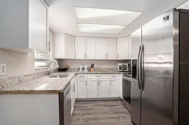 a kitchen with stainless steel appliances granite countertop a sink stove and refrigerator