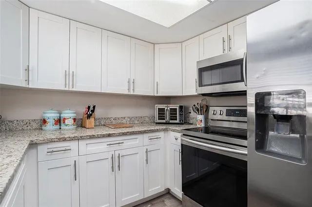a kitchen with granite countertop white cabinets stainless steel appliances and a sink