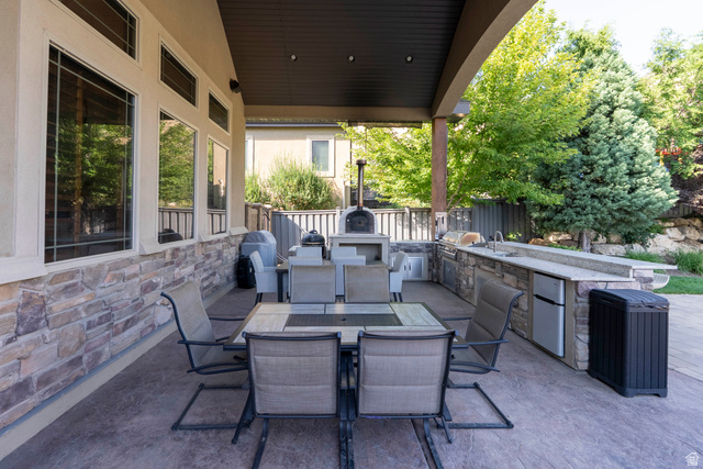 687 South 2080th Street East Springville, UT 84663 - Photo 115 of 149 Covered patio with a stone facade, featuring an outdoor kitchen with an integrated sink, built-in refrigerator, and stone countertops