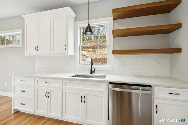 a kitchen with white cabinets and a window