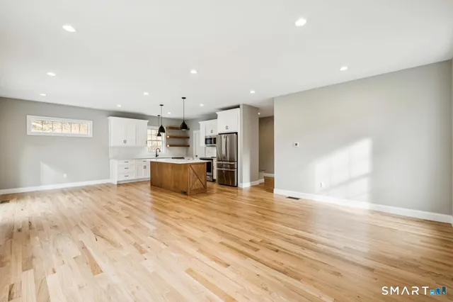 a view of a kitchen with kitchen island a sink wooden floor and a refrigerator