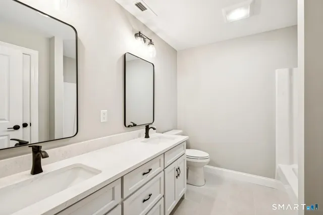 a bathroom with a double vanity sink toilet and mirror