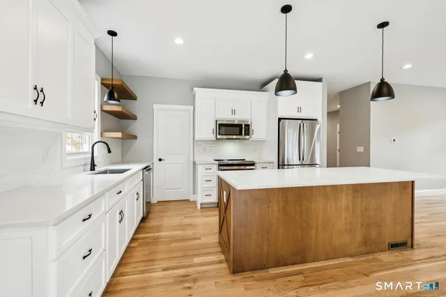 a kitchen with kitchen island a counter top space a sink a stove and refrigerator