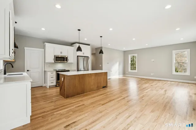 a large kitchen with stainless steel appliances a large counter top a sink a refrigerator and a stove