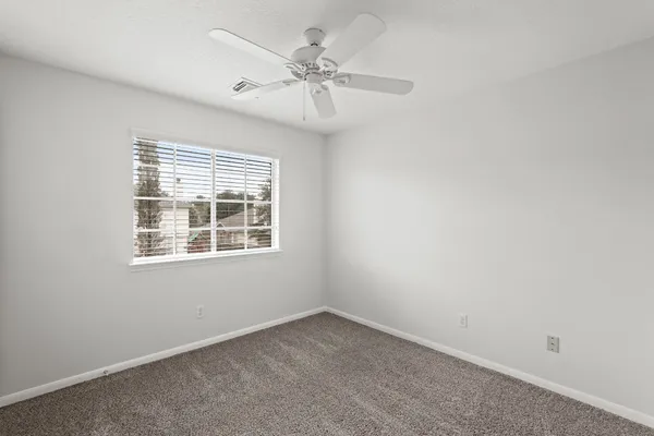 an empty room with a window and a fan