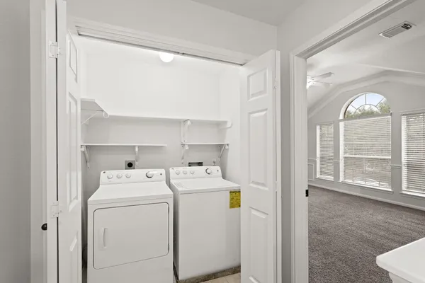 a view of washer and dryer with bathroom in the background