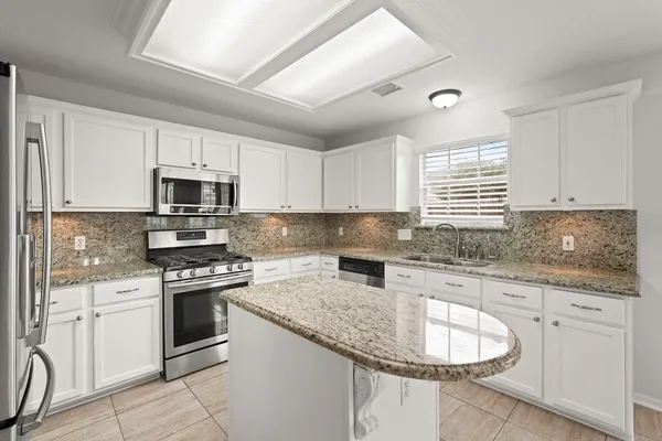 a kitchen with granite countertop a sink stove and cabinets