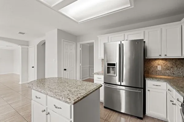 a kitchen with stainless steel appliances granite countertop a refrigerator a stove and white cabinets