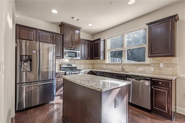 a kitchen with stainless steel appliances granite countertop a sink stove and refrigerator