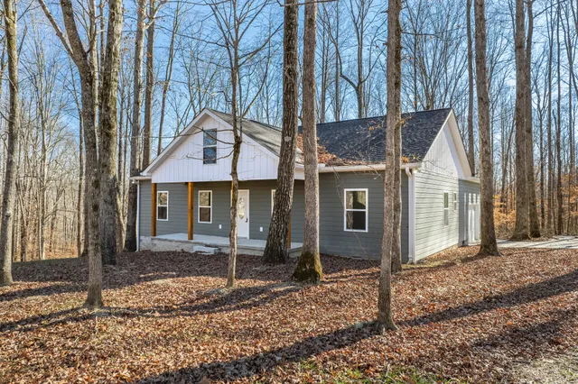 a view of a house with a yard and large tree
