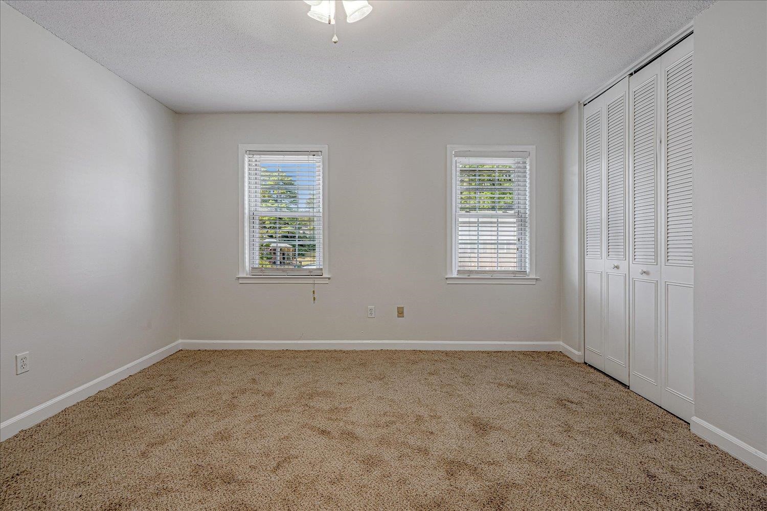 5696 Quince Road, Unit 1 Memphis, TN 38119 - Photo 16 of 26 Unfurnished bedroom with a closet, multiple windows, light colored carpet, and a textured ceiling